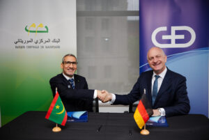 The Governor of the Central Bank of Mauritania and the CEO of G+D shaking hands after signing a digital currency agreement.